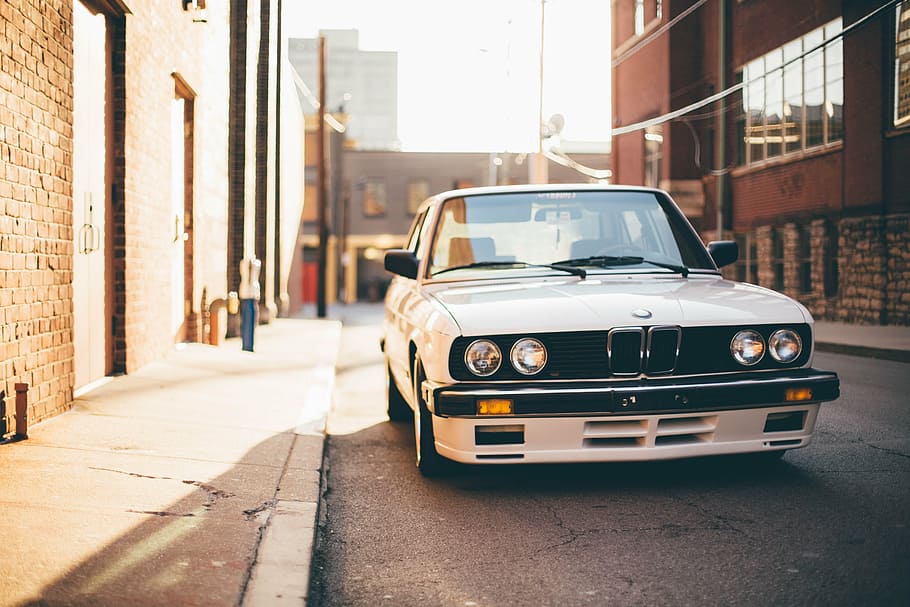 white BMW M3 E30 parked near concrete building during daytime