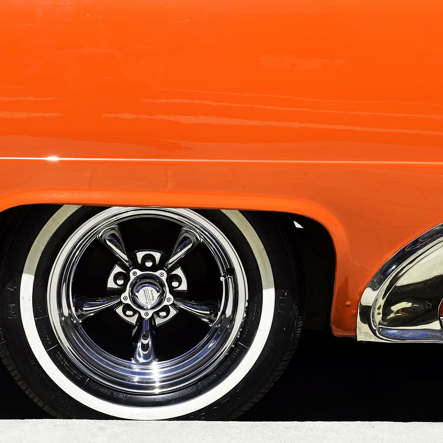 classic orange vehicle with chrome 5-spoke vehicle wheel and white wall tire