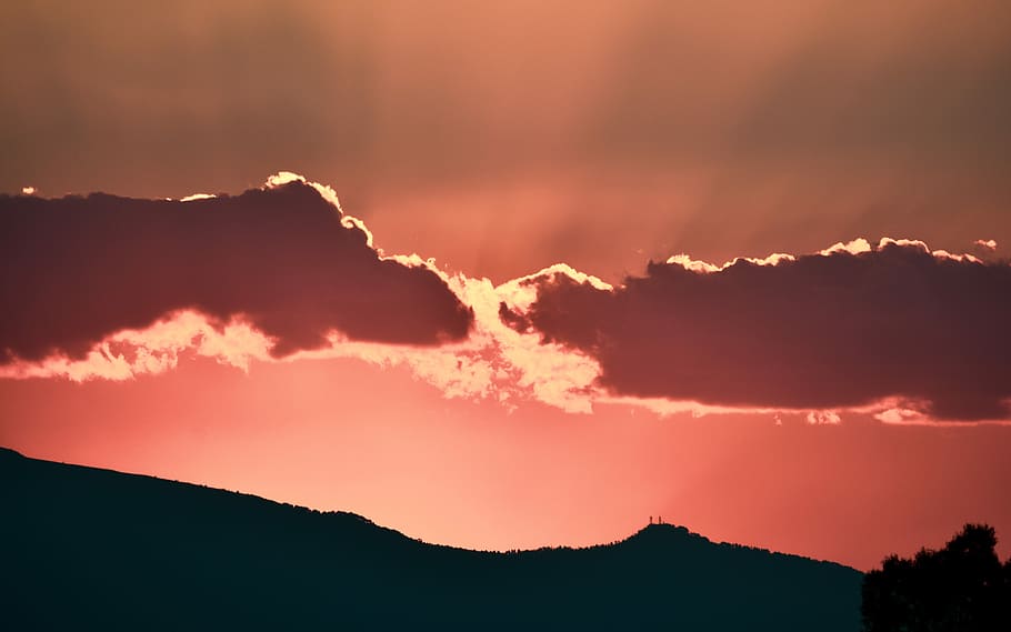silhouette photo of mountain during golden hour, sunlight across two gray clouds during sunset HD wallpaper
