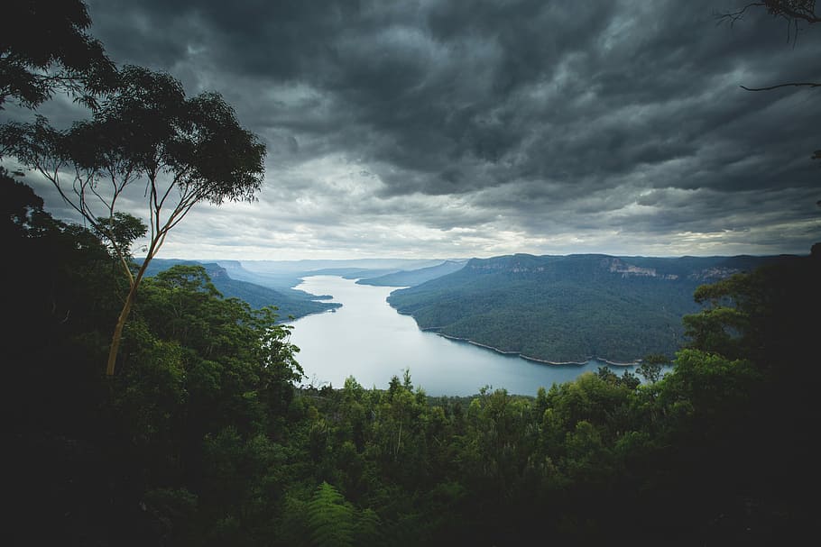 lake surround by mountains under nimbus clouds, body of water between two landmasses HD wallpaper