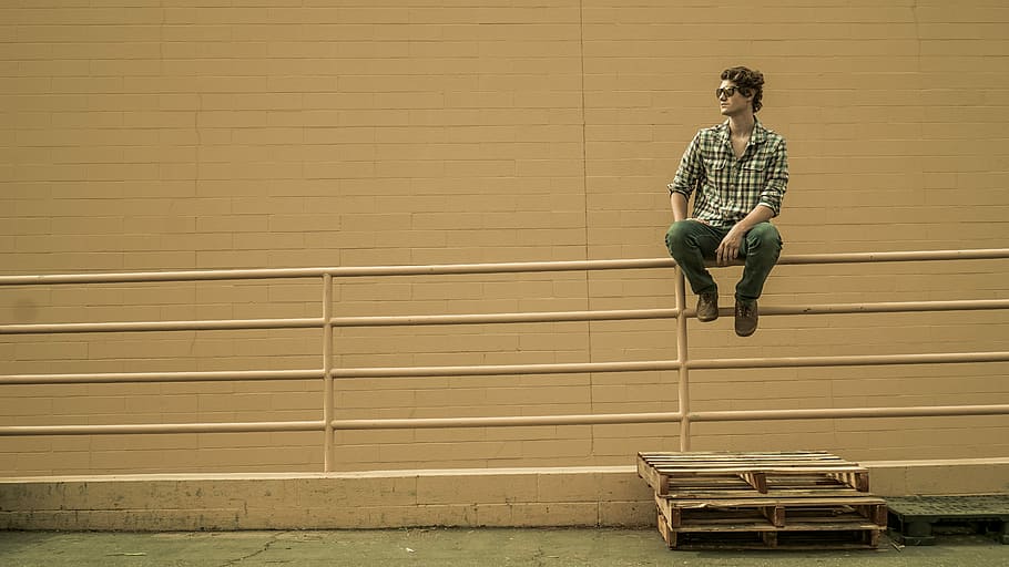 man sitting on white metal barricade, man seating on fence, rail HD wallpaper