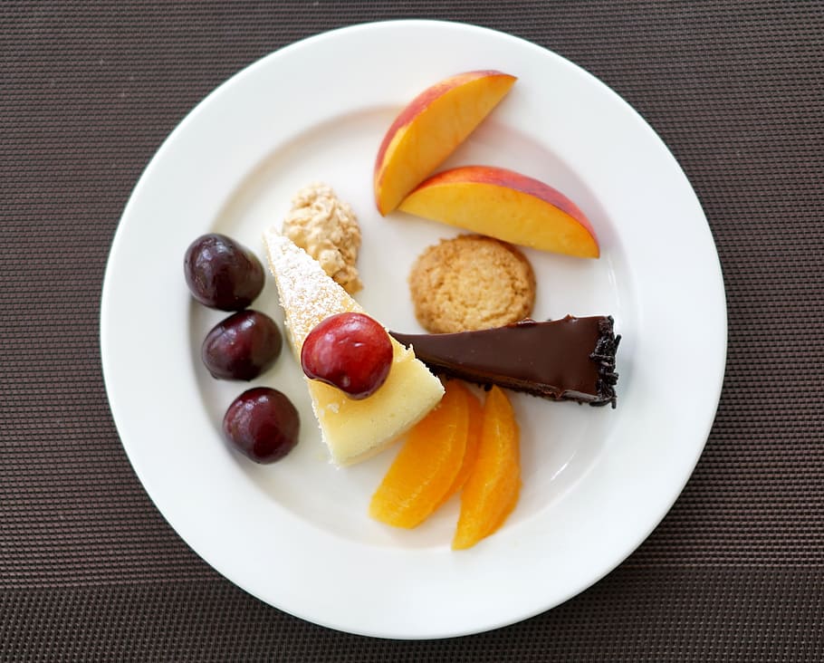 two sliced cakes with sliced fruits on round white ceramic plate HD wallpaper