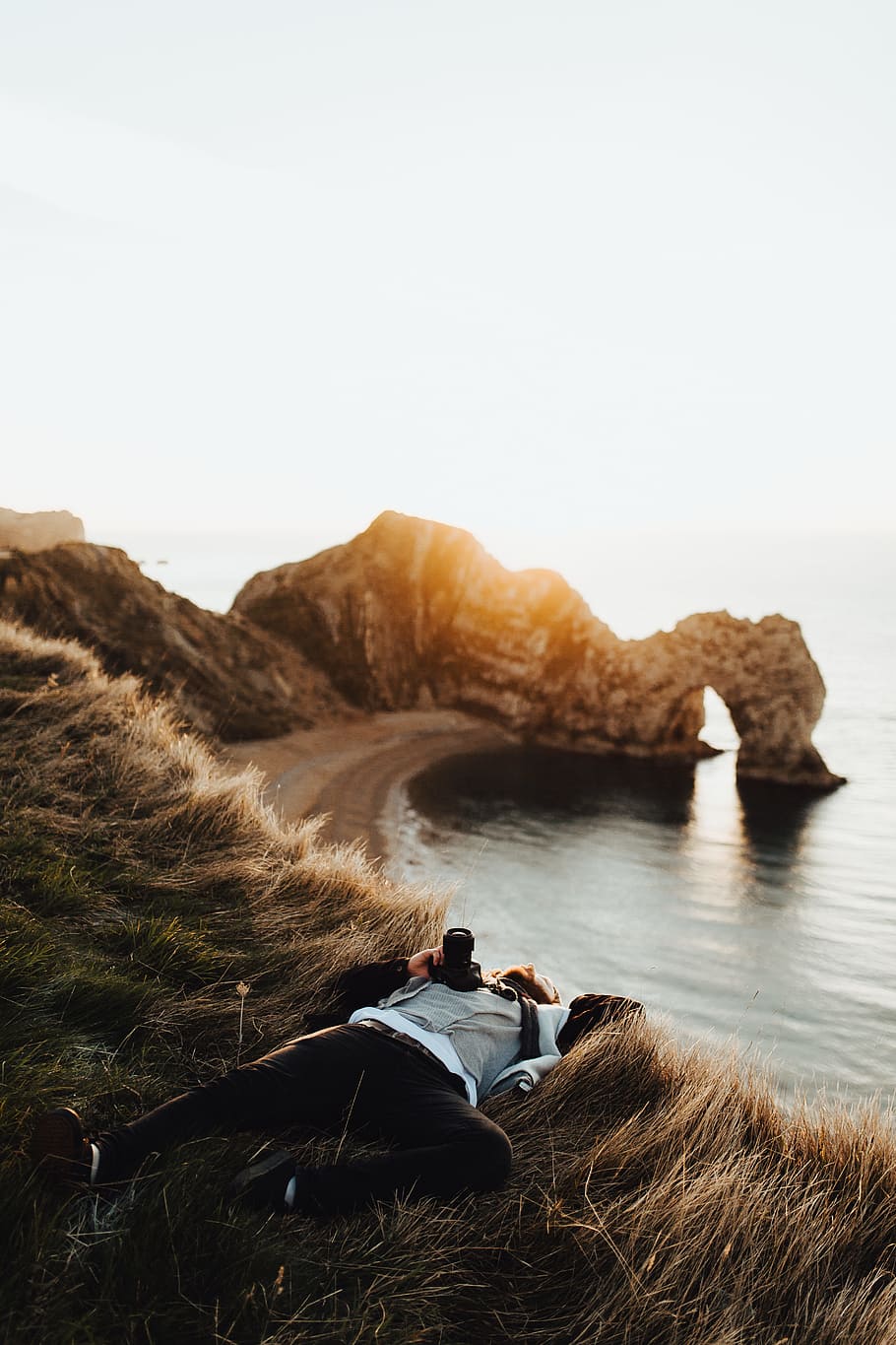 Dorset, man laying on brown grass near cliff and body of water, HD wallpaper