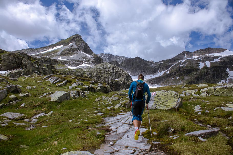 man running near rocky mountain during daytime, man walking on mountain HD wallpaper