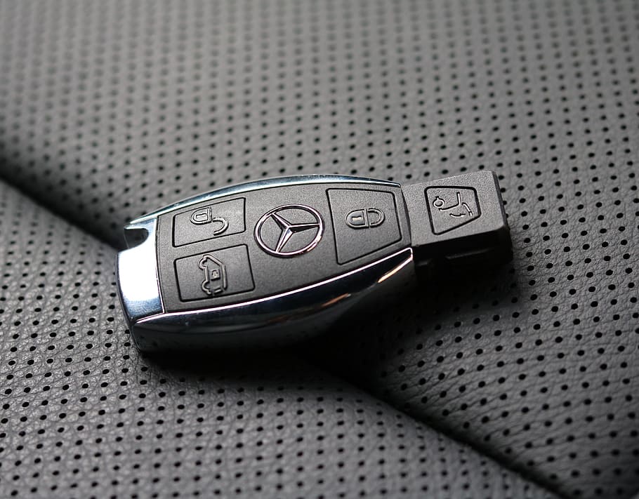 black and gray Mercedes-Benz vehicle fob on gray textile, car keys