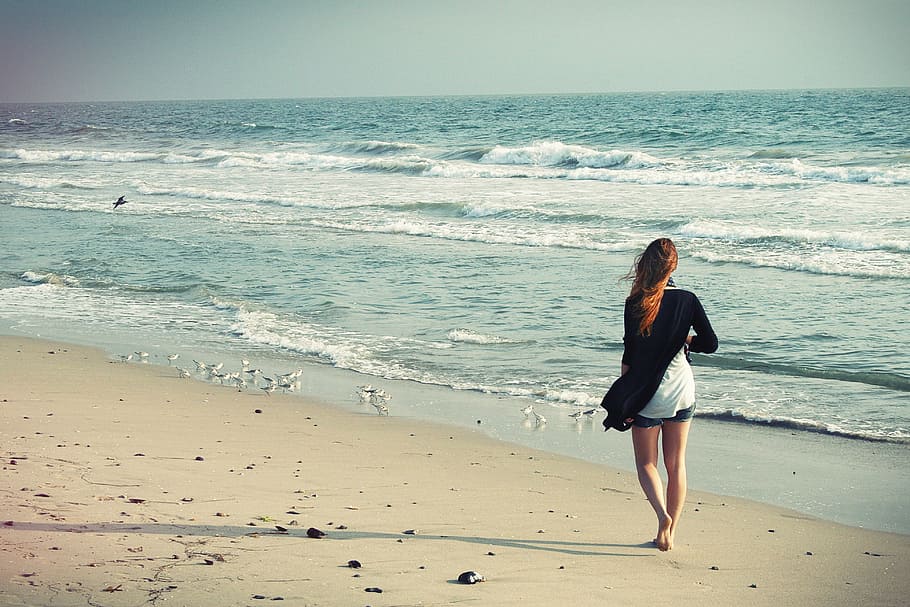 woman walking beside of beach during daytime, beach woman, walking away