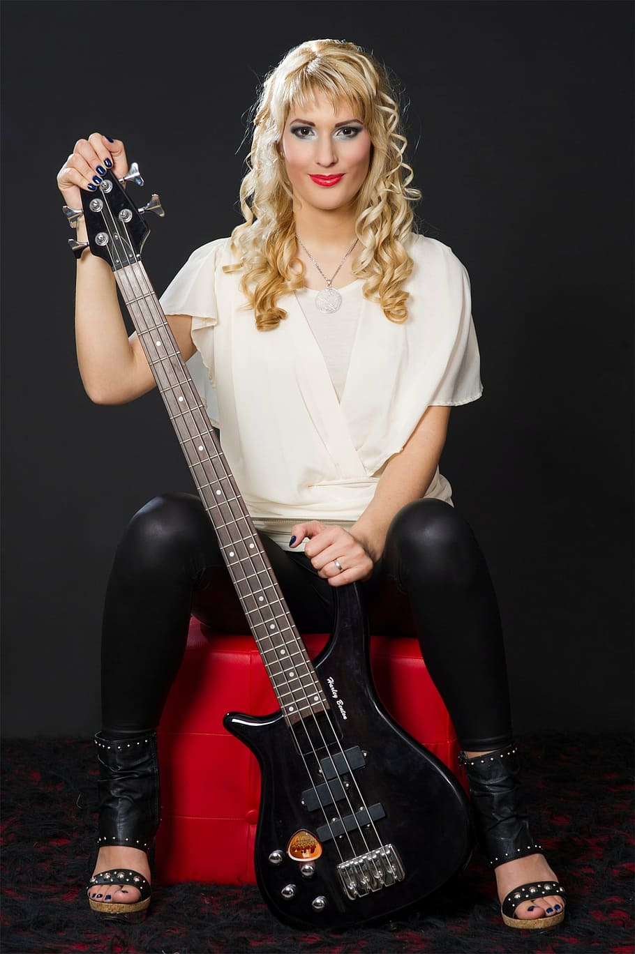 woman holding black 4-stringed electric bass guitar, musician