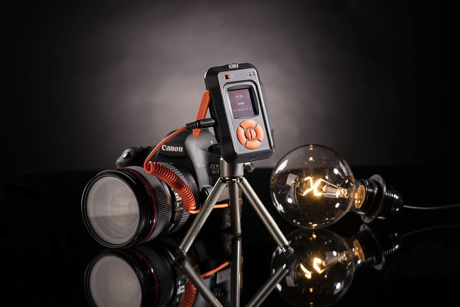 black Canon DSLR camera with bulb, Canon DSLR camera beside light bulb HD wallpaper