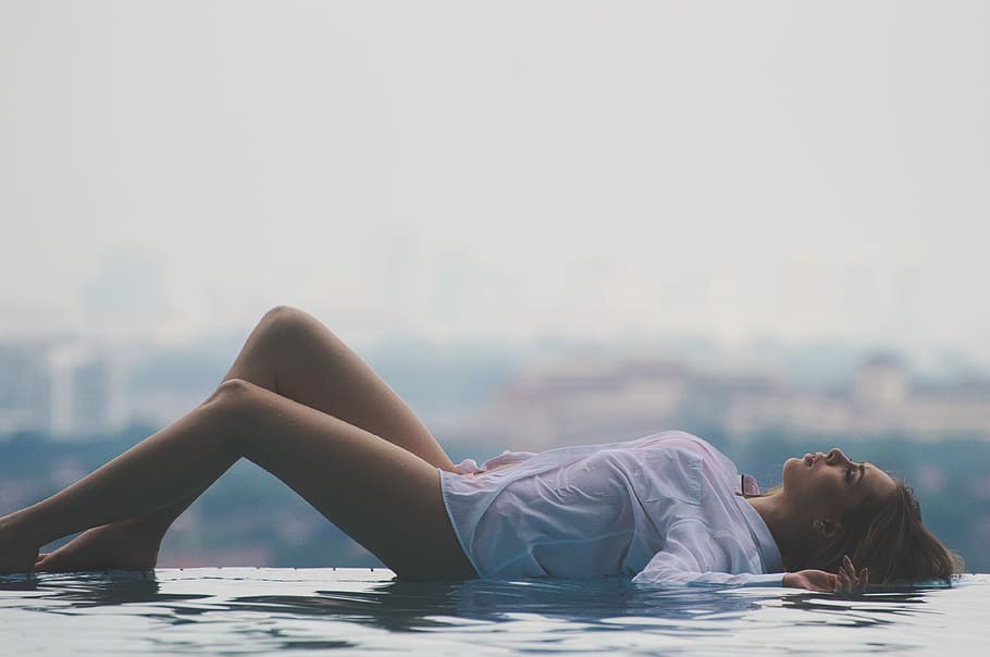 woman lying on pool during daytime, woman lying on side of swimming pool during daytime
