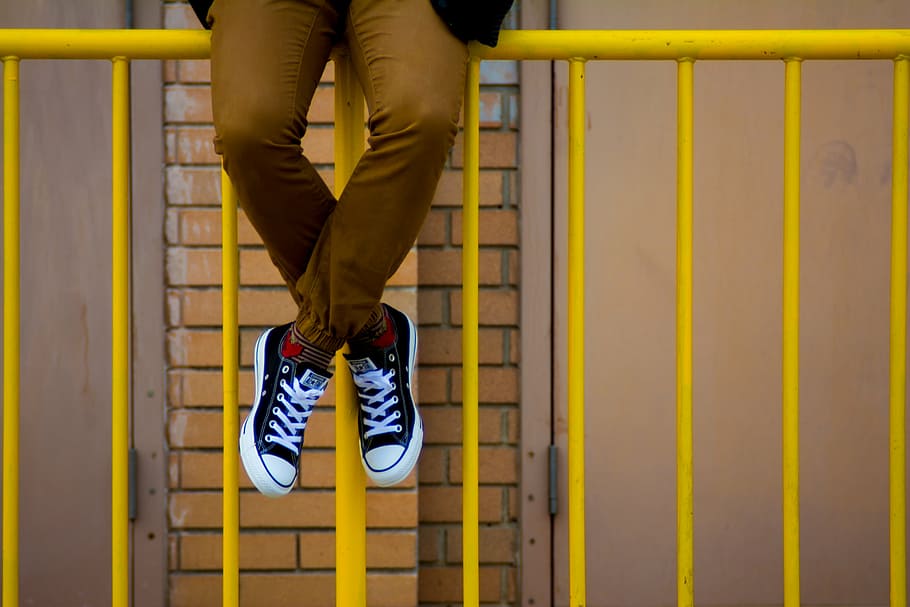 person sitting on yellow fence, man, wearing, black, converse, HD wallpaper