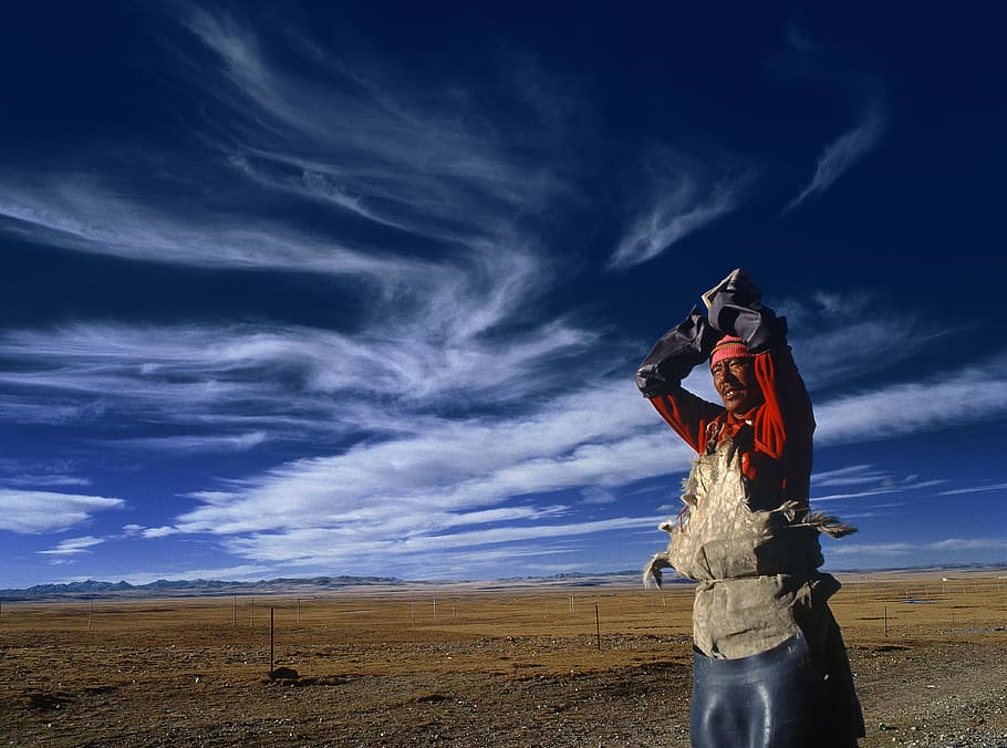 man standing near gray steel fence under white clouds during daytime, man wearing red suit standing outside below blue sky HD wallpaper