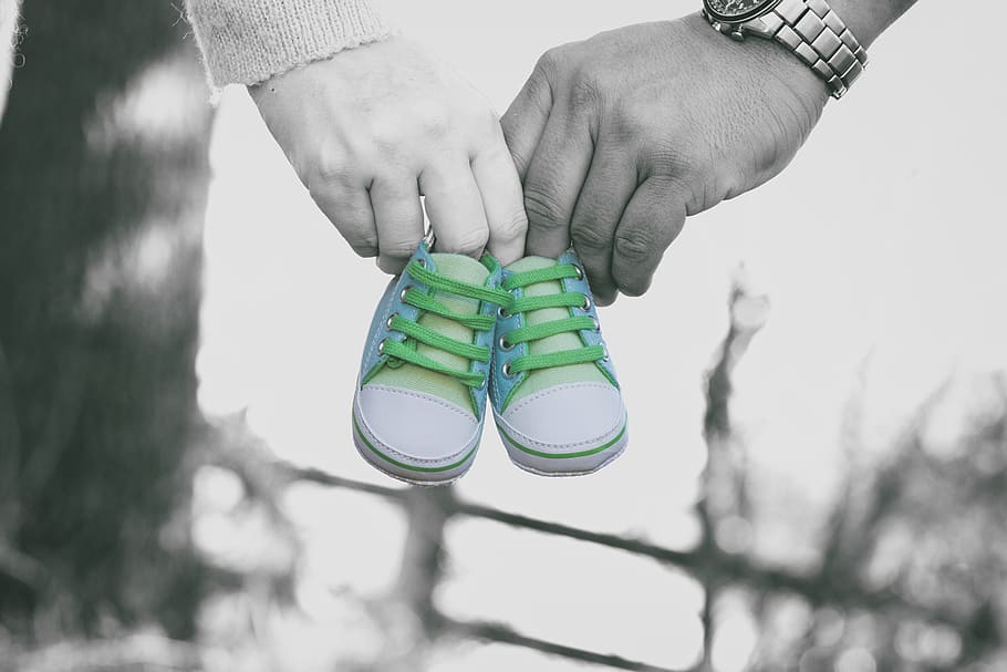 selective color photo of man and woman holding white-and-gray baby shoes, HD wallpaper