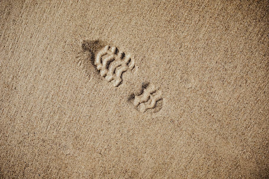 selective focus photography of foot print, brown sand with shoe print