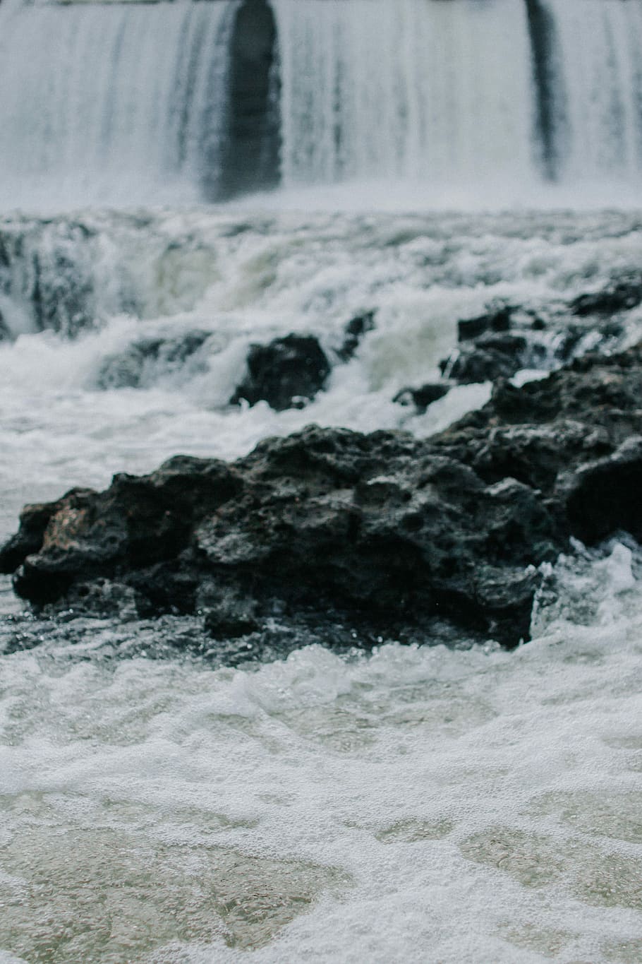 selective focus photography of black rock in waterfalls at daytime, long exposure photo of body of water and rock formations HD wallpaper