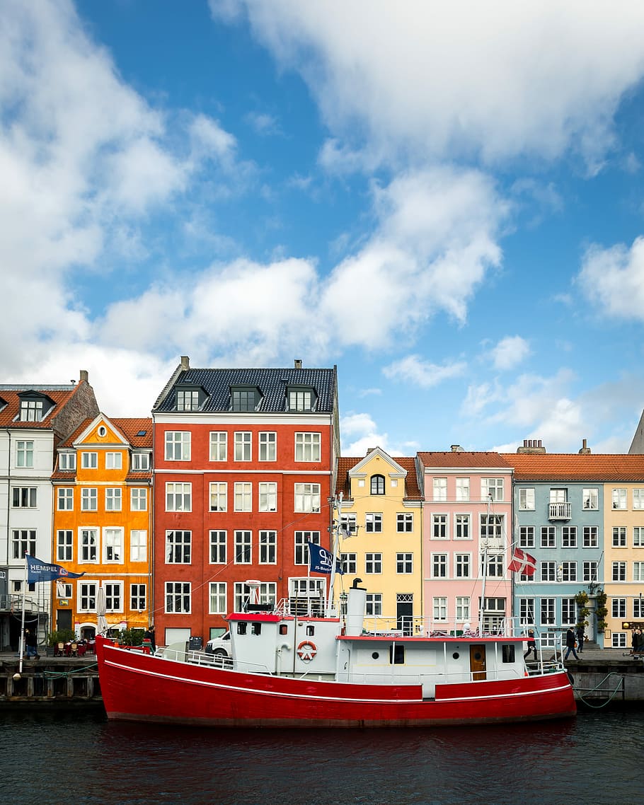 Colorful Harbour, red and white motored boat on water body under blue sky and white clouds
