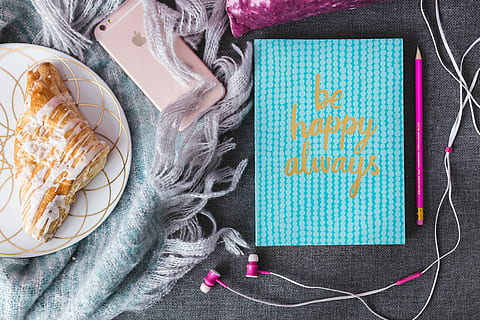 Blue notebook with a pink iPhone, headphones and a sweet bun HD wallpaper