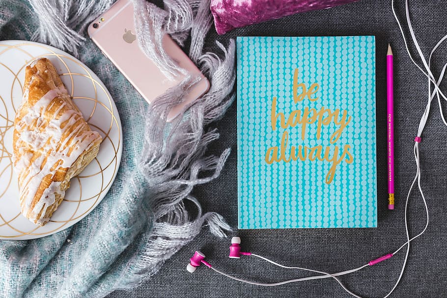 Blue notebook with a pink iPhone, headphones and a sweet bun HD wallpaper