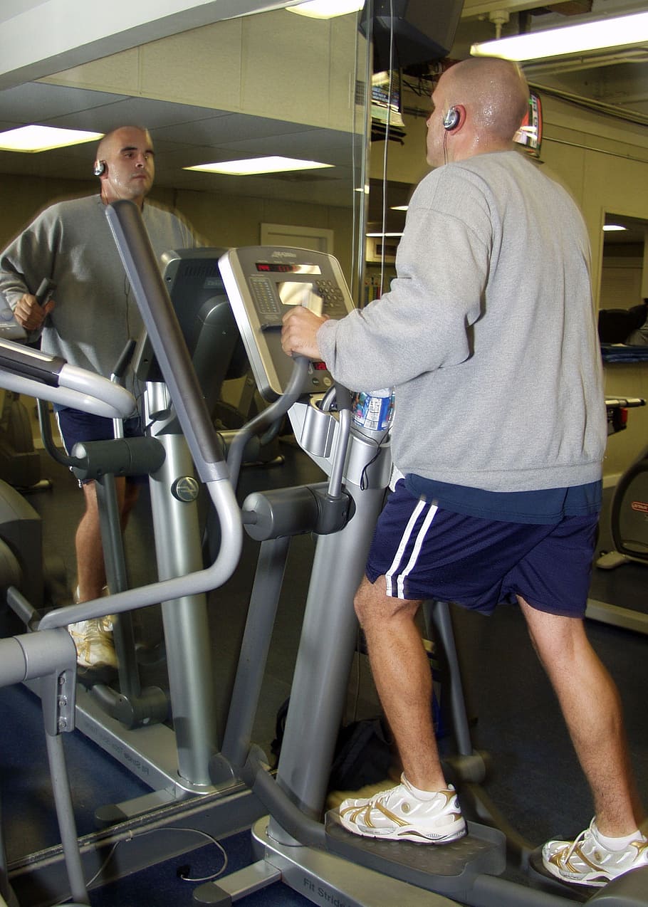 man riding on elliptical trainer, gym room, fitness, cardiovascular exercise