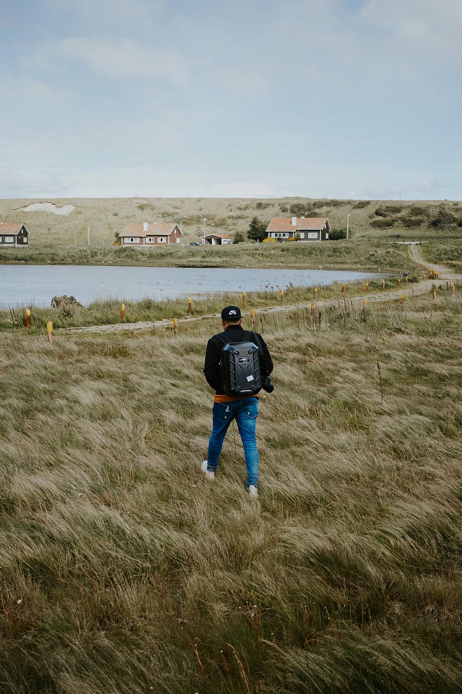 person wearing blue denim skinny jeans and black jacket walking on the grass, person walking on grass field HD wallpaper