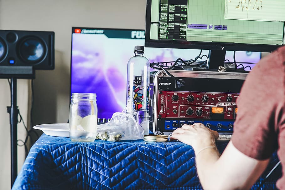 person using computer beside clear glass bottle and jar on blue tablecloth, person holding on tablecloth HD wallpaper