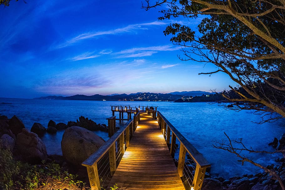 brown dock with light beside rock formation at daytime, brown wooden deck leading to body of water under blue sky HD wallpaper