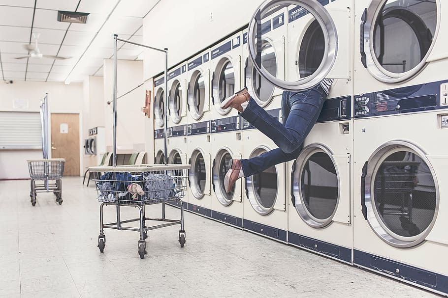 photo of person getting something inside dryer, laundry, washing machines