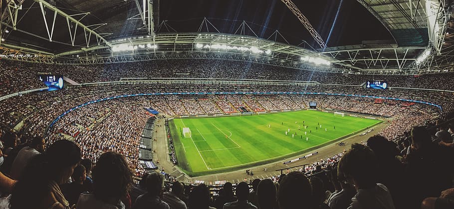 green football field surrounded by people during nighttime HD wallpaper