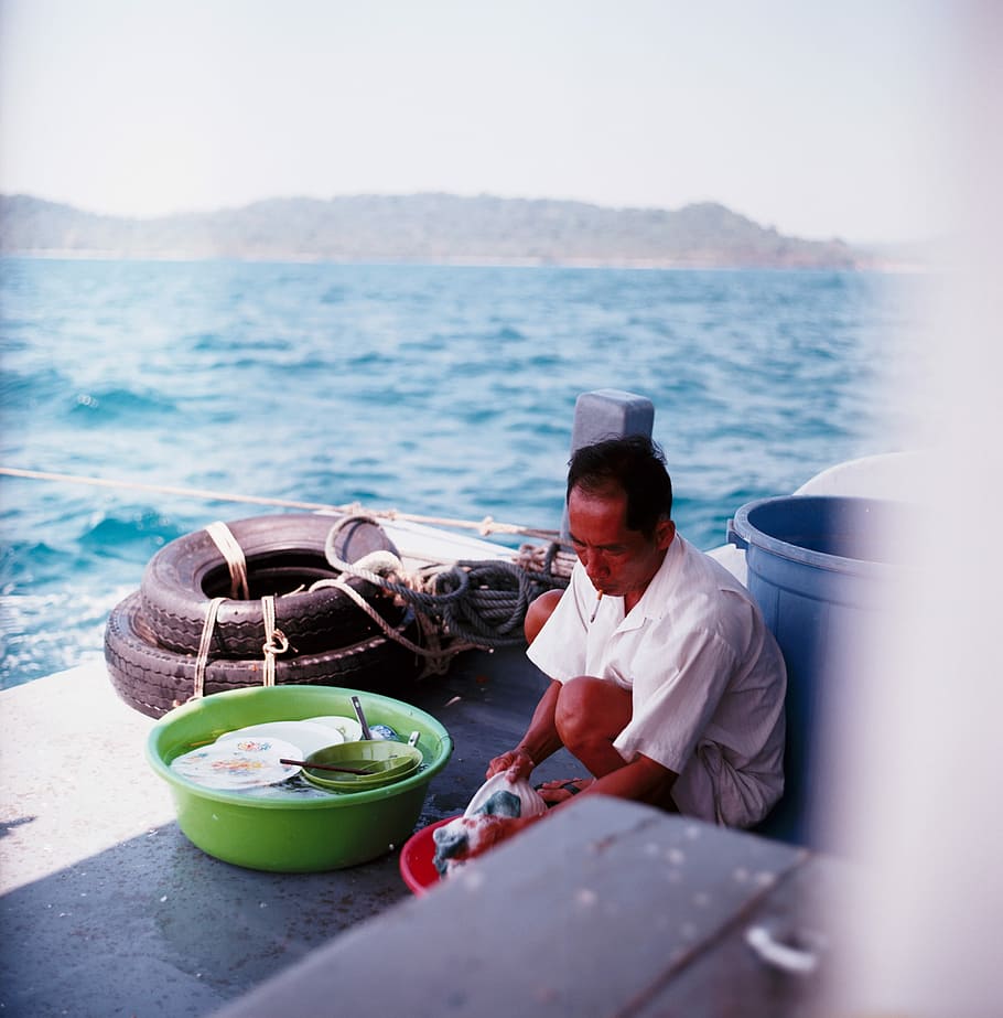 man washing dishes beside blue plastic pail, man washing dishes beside sea HD wallpaper