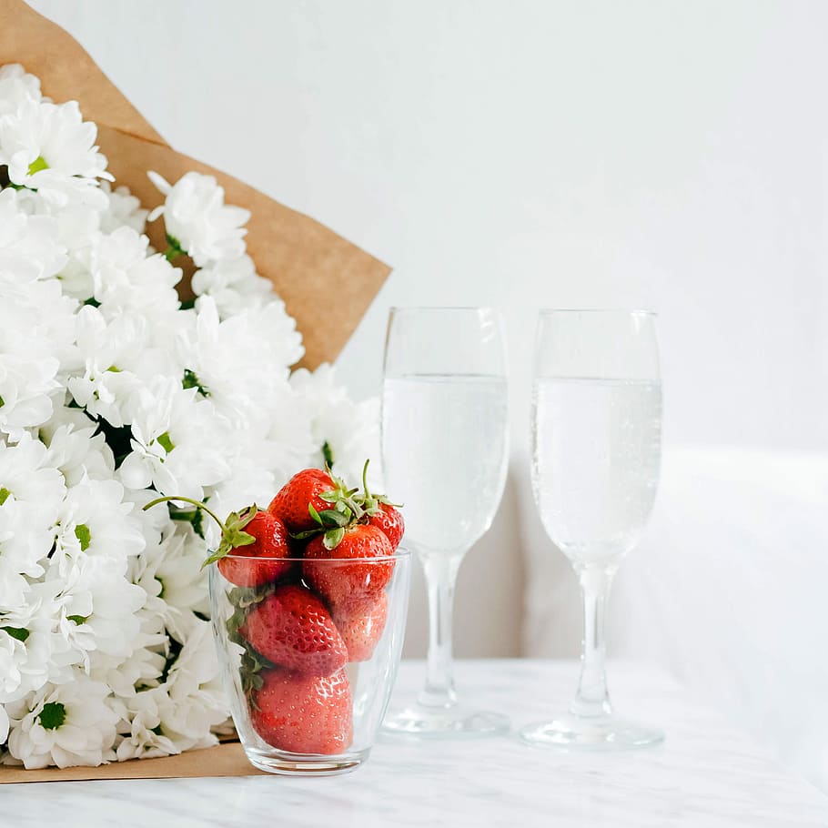 red strawberries filled glass cup beside white flower bouquet, strawberries beside white flowers, HD wallpaper