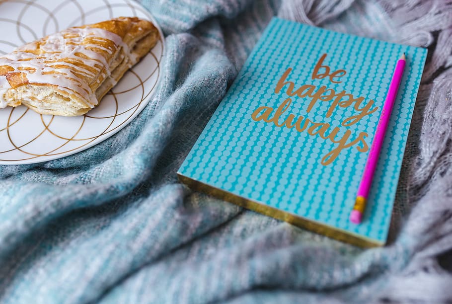 Blue notebook with a pink iPhone, headphones and a sweet bun HD wallpaper