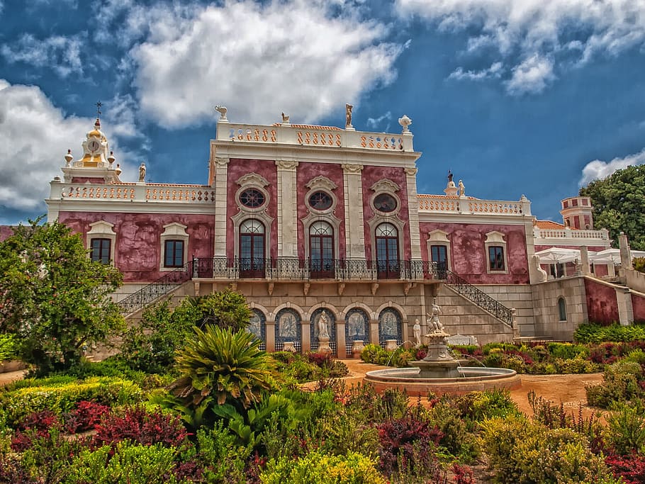 photo of a red and brown castle near garden and fountain, palace of estoi