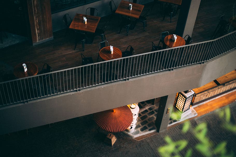 aerial photography of concrete establishment, round and square brown wooden table on balcony HD wallpaper
