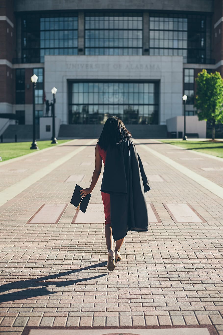 woman standing at facade of Alabama University building, woman walking towards University of Alabama building