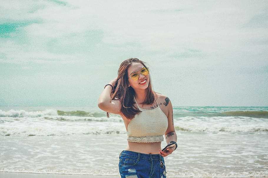 woman standing while holding her hair, woman wearing crop top beside the seashore HD wallpaper