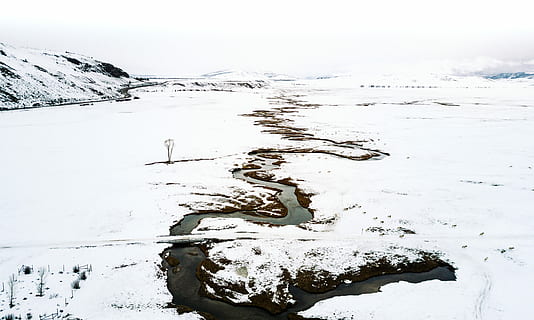 landscape photography of snow covered land, water flowing on river in the middle snow covered terrain HD wallpaper