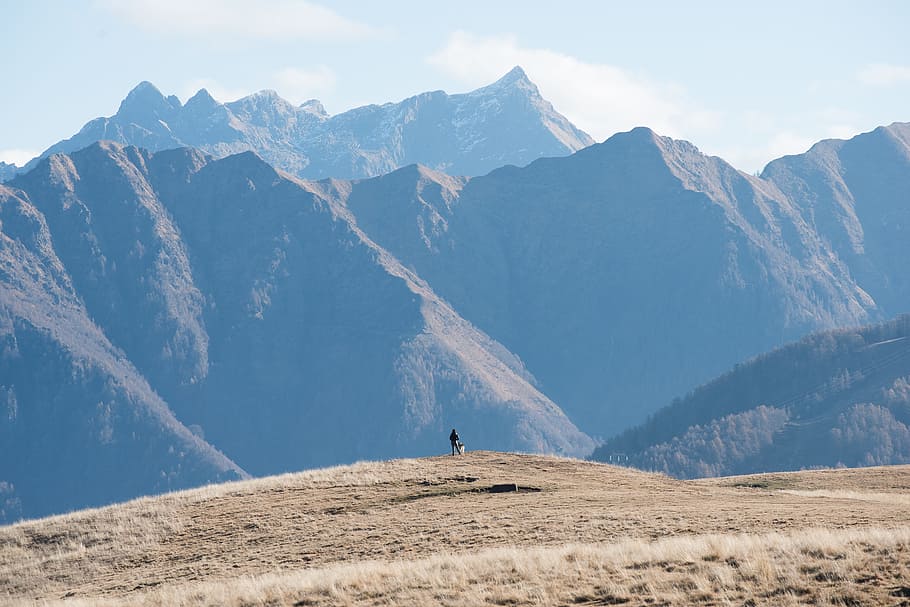 photo of person facing mountain, person standing on cliff under clear sky during daytime HD wallpaper
