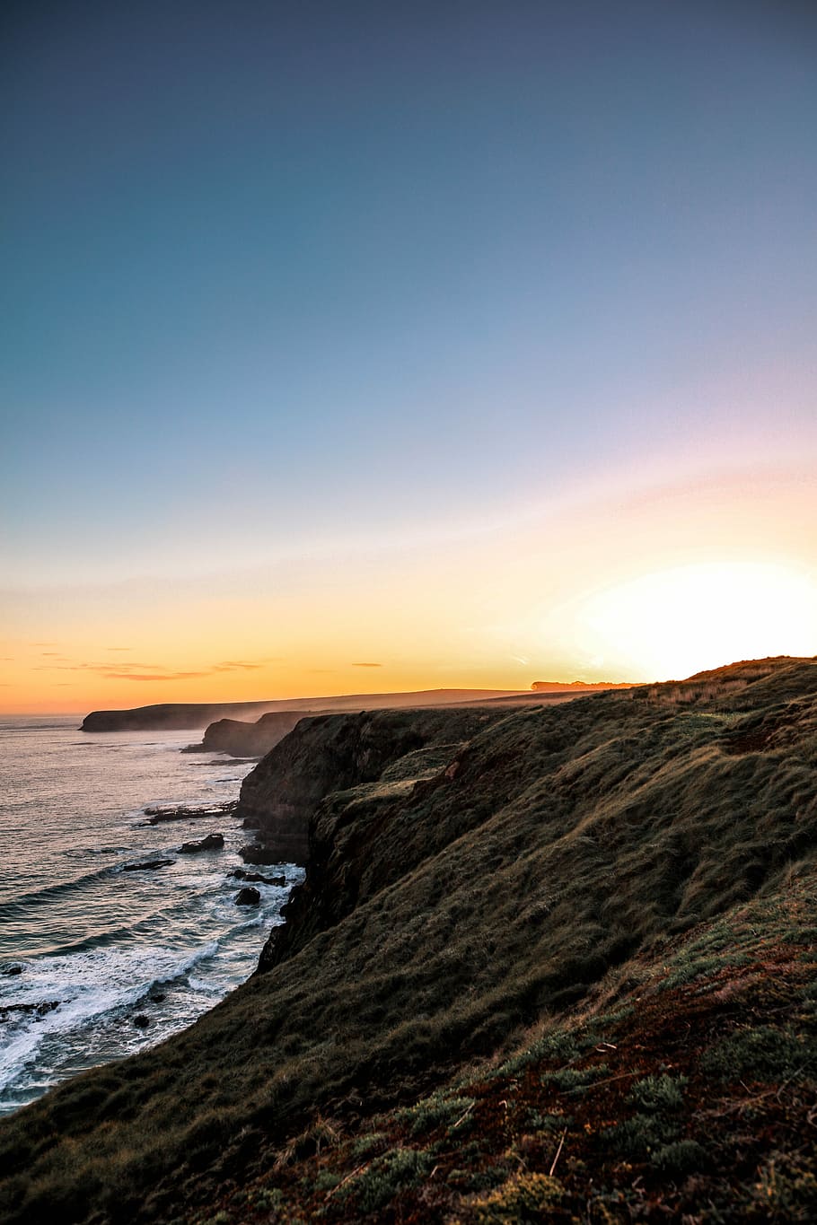 brown mountain cliff during daytime, rock formation near sea under blue sky during daytime HD wallpaper