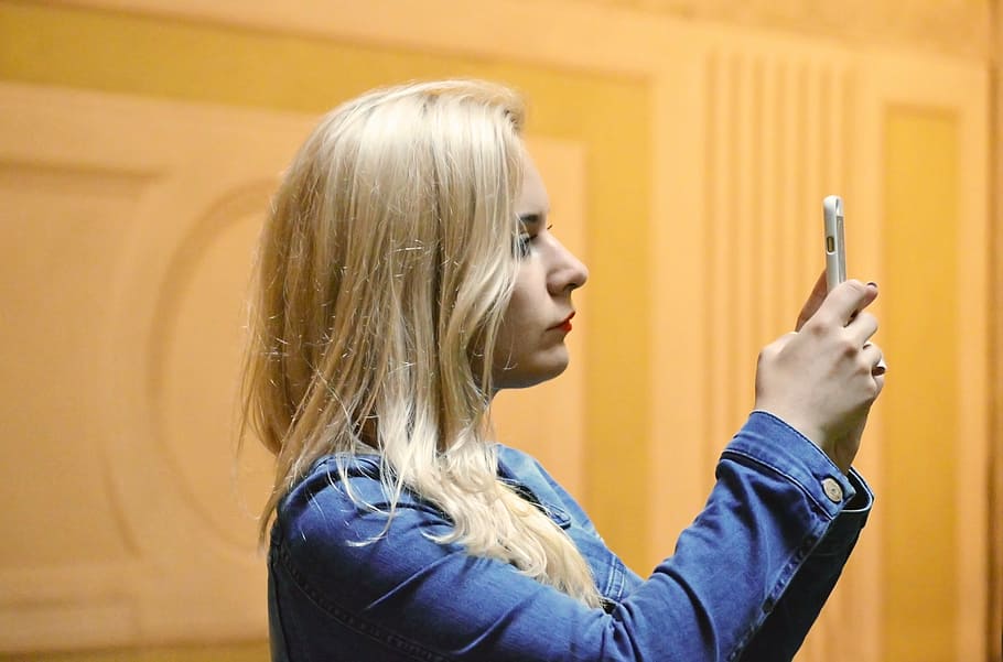 woman holding smartphone taken on lighted room, blonde, female