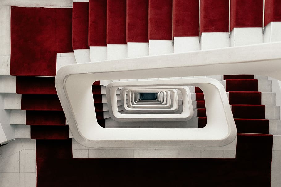 high-angle photo of spiral stairs with red carpet, white-and-red spiral stairs
