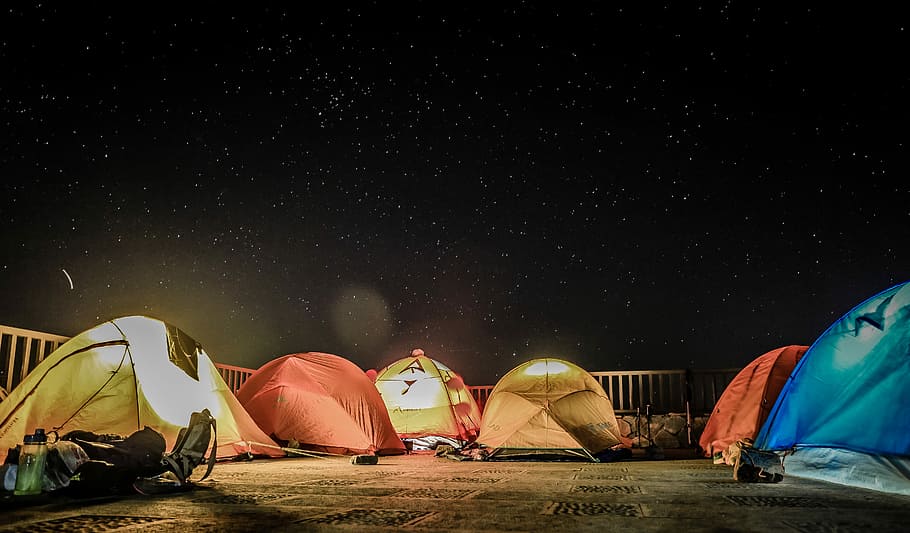 assorted-color dome tents beside fence, camping tents under starry sky