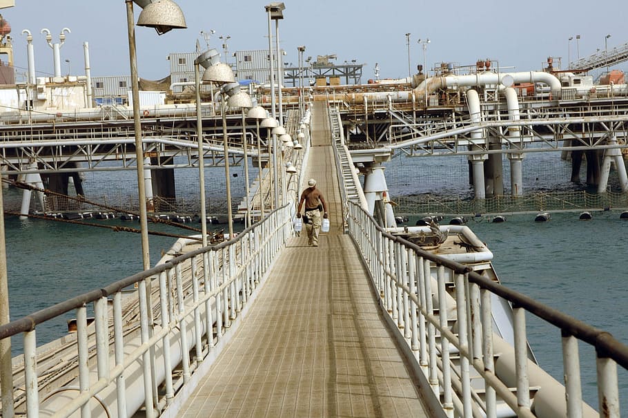 male walking on bridge carrying containers, persian gulf, walkway