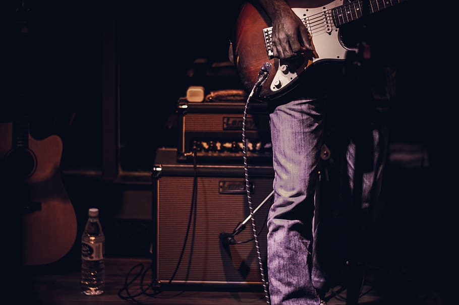man playing guitar inside dark room, man on stage holding electric guitar HD wallpaper