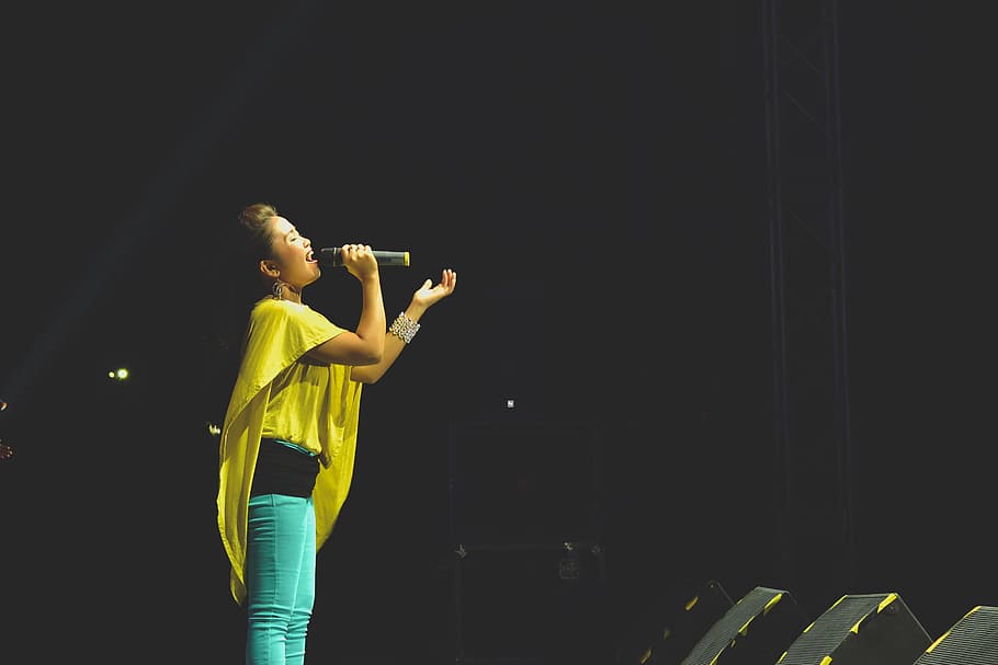woman holding a microphone performing on stage, woman holding microphone singing on stage HD wallpaper