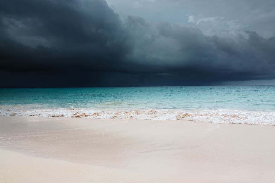 photo of black storm near seashore during daytime, dark clouds