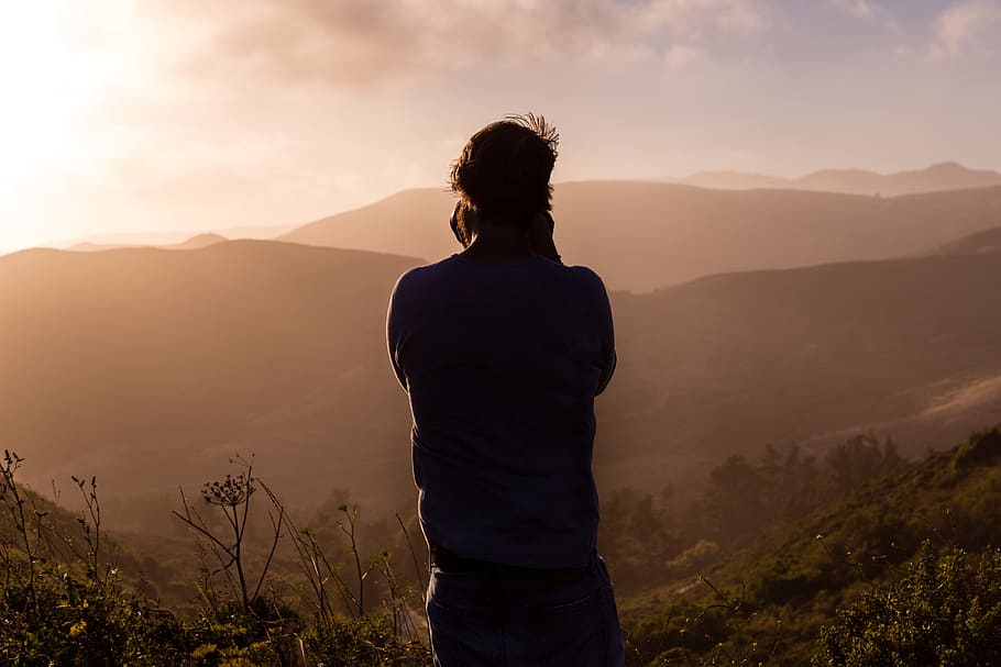 person shouting on top of mountain, photography of a man in the top of mountain during sunset
