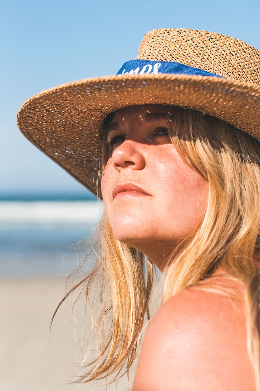 close-up photo of woman wearing brown wicker sun hat near beach during daytime