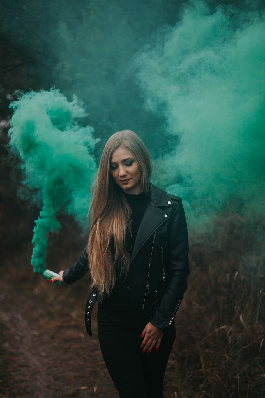 woman wearing green jacket holding green bottle with smoke, female