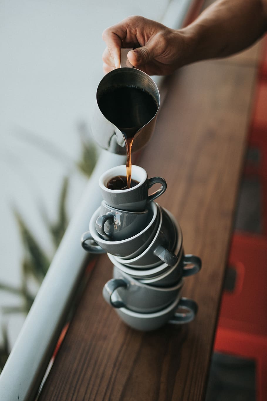 person holding gray stainless steel pitcher bside window, person pouring coffee on white stacked teacups HD wallpaper