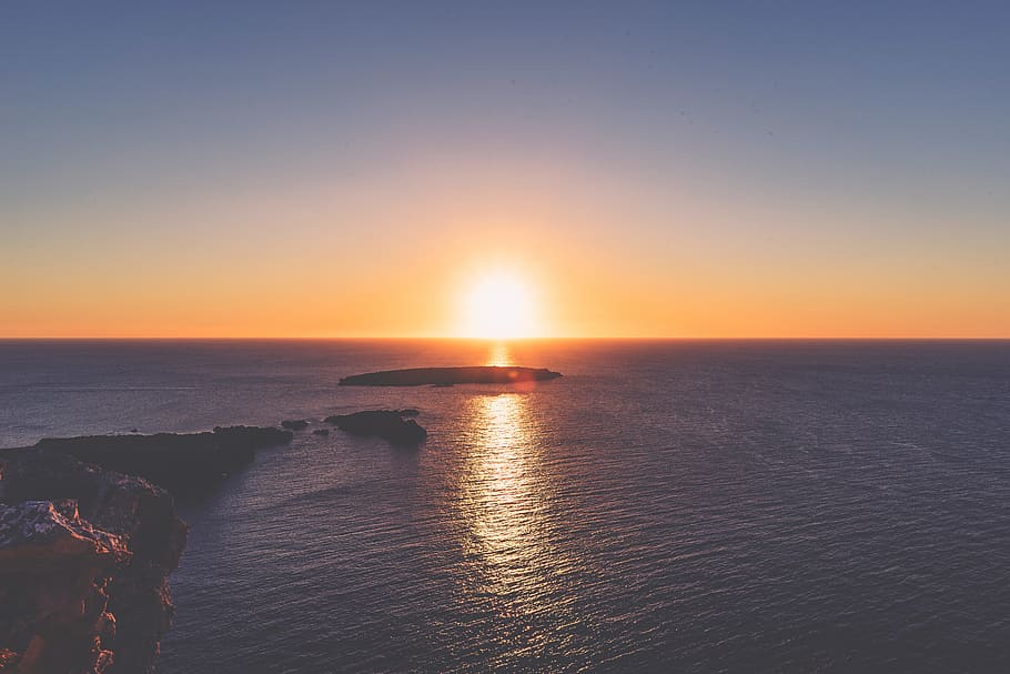 rock on body of water during sunset \, landscape photography of island surrounded by calm seas during golden hour HD wallpaper
