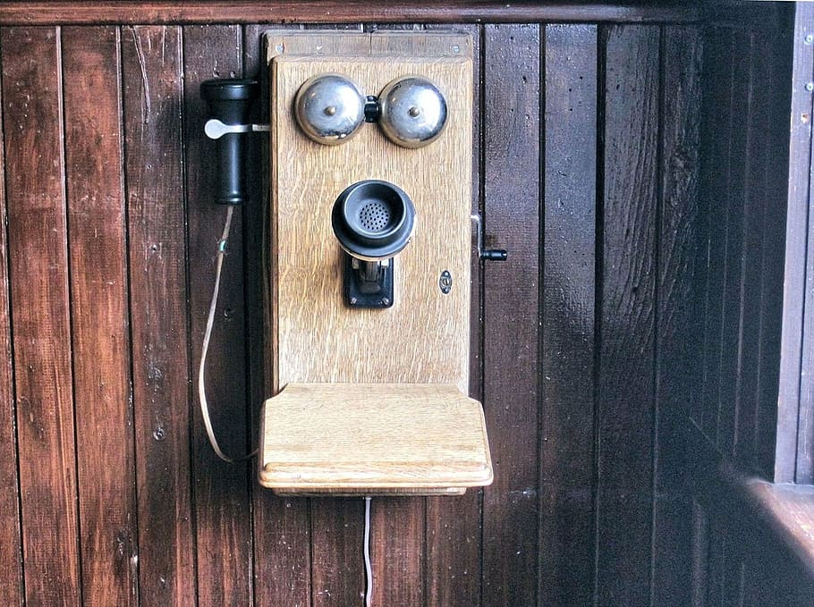 vintage brown and black telephone on brown wooden wall, old wall crank telephone